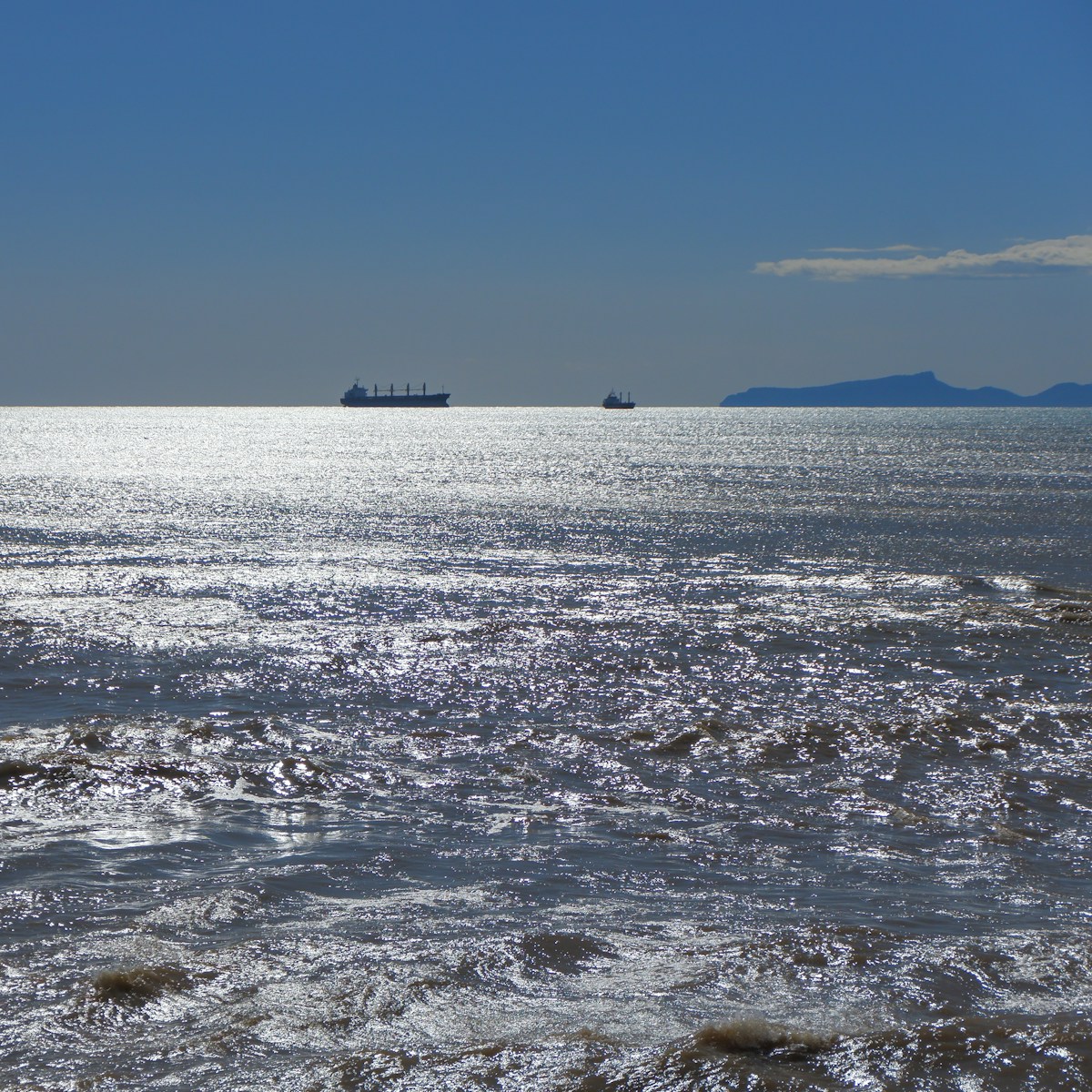 a large body of water with a boat in the distance